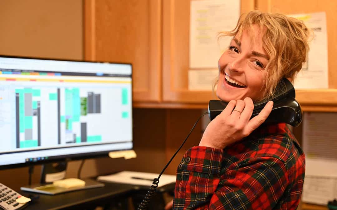 Amy sitting in front of a computer and answering the phone